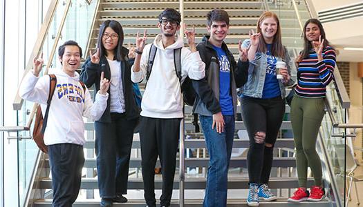 smiling students pose on the stairs